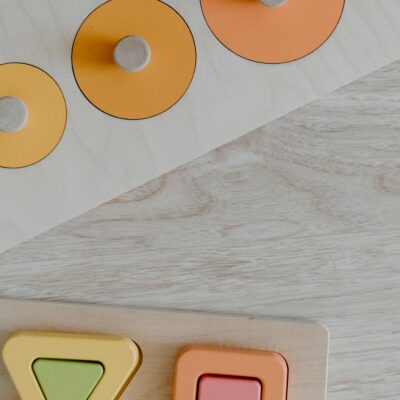 Colorful wooden puzzle pieces on a light wood surface, featuring geometric shapes for kids.